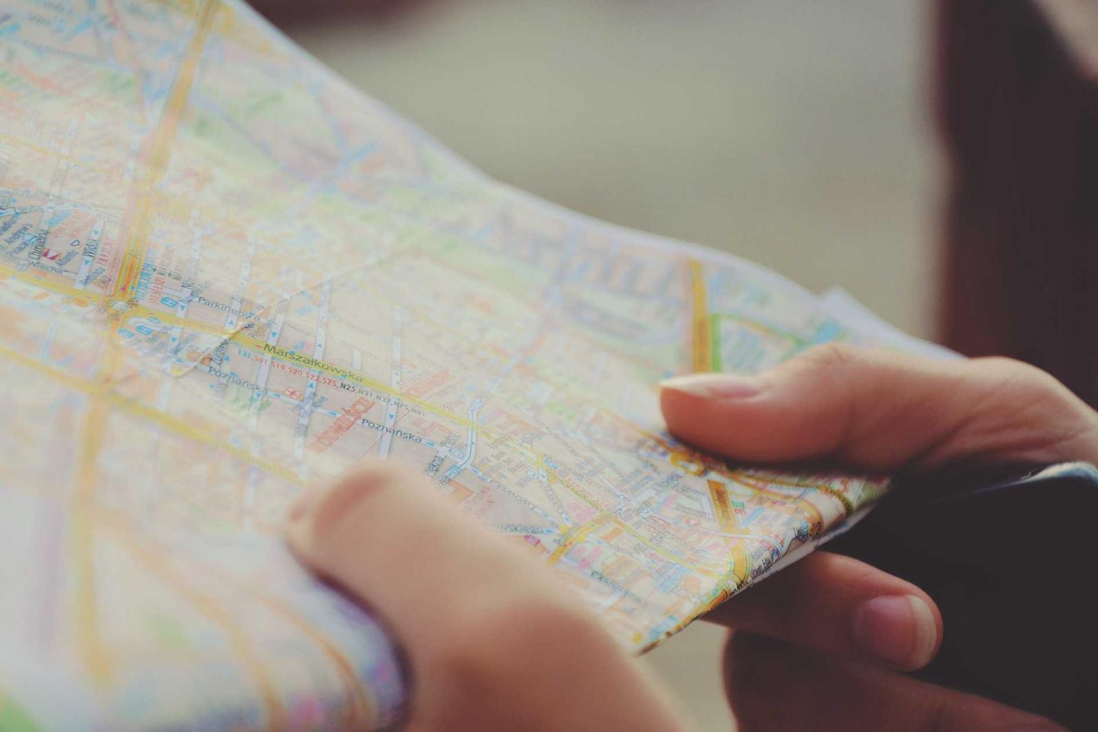 Two hands holding a folded paper street map