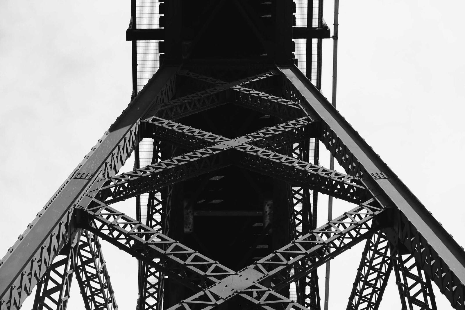 Black and white view up into the steel lattice of a tall truss tower